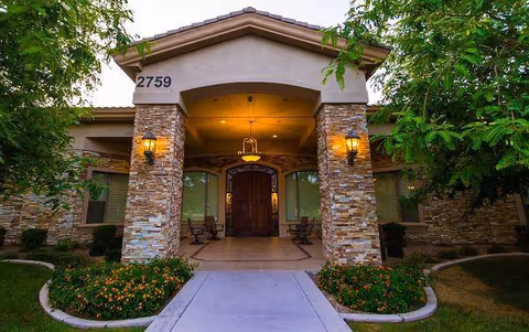 Entrance to a senior living facility with stone pillars and warm lighting.