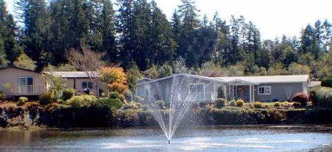 Lakeside view of The Lakes at Gig Harbor with a fountain and low buildings.