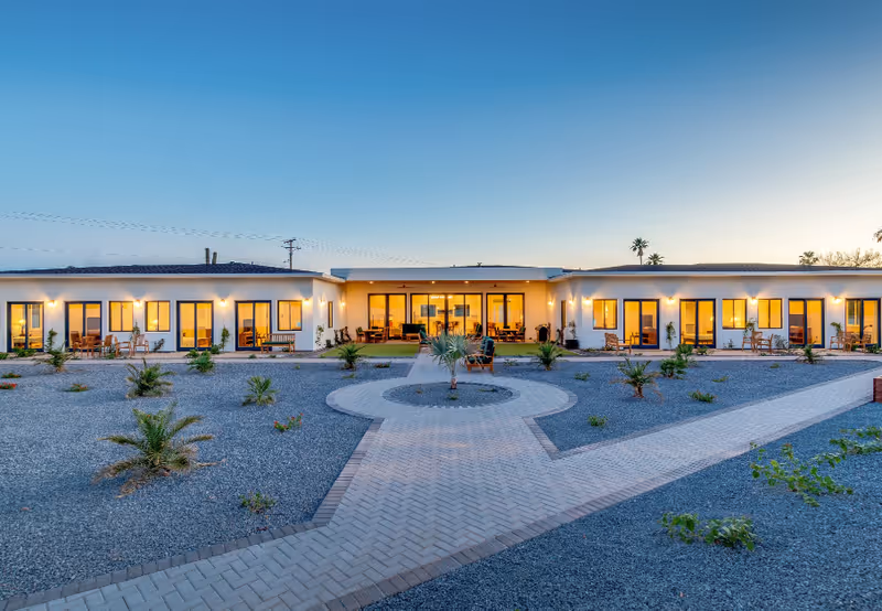 Low-rise senior living center with illuminated windows and an outdoor courtyard.
