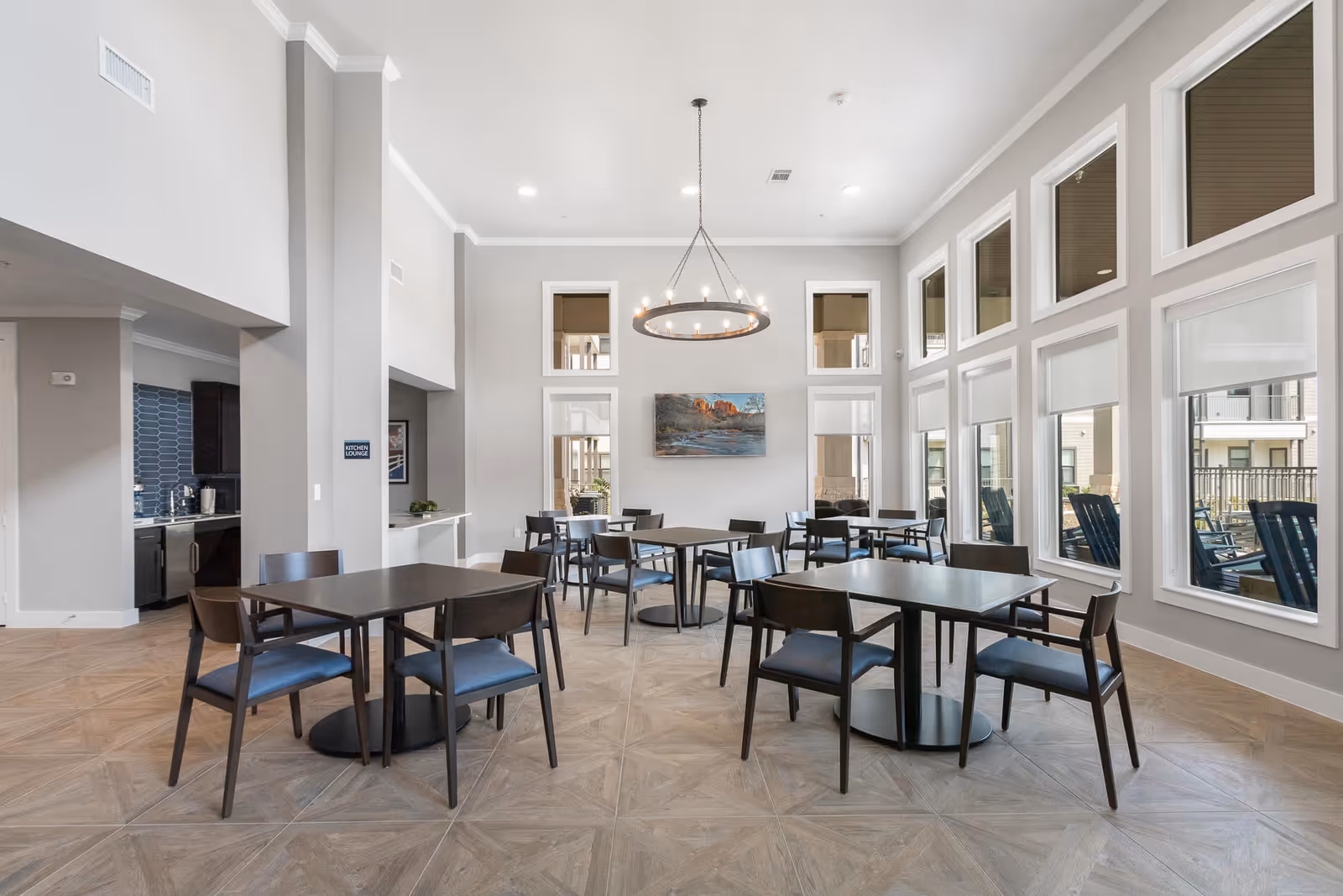 Interior view of the dining room at Solea Cinco Ranch, featuring several tables and chairs, large windows, and a modern chandelier.