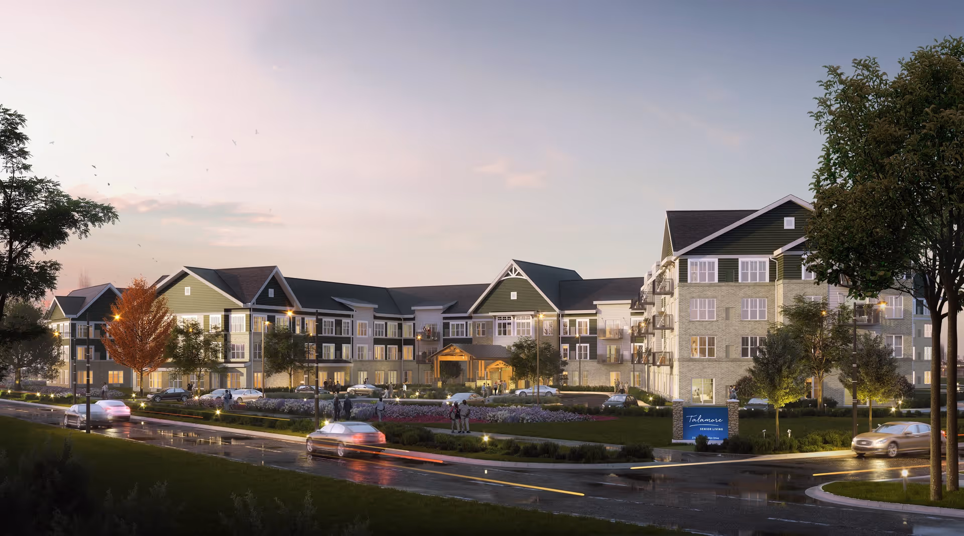 Exterior view of Talamore Senior Living Woodbury building at dusk with cars on the road and people walking near the entrance surrounded by trees and landscaped greenery.