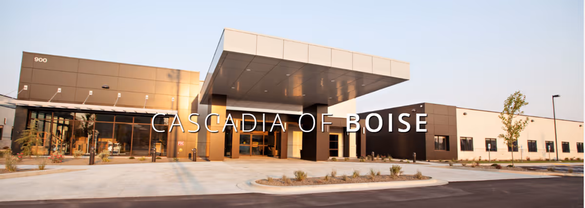 Exterior front view of Cascadia of Boise facility showing a modern building with large windows, a covered entrance, and landscaped surroundings under a clear sky.
