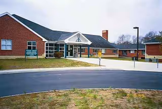 Front view of a brick senior living center with glass entrance and canopy.