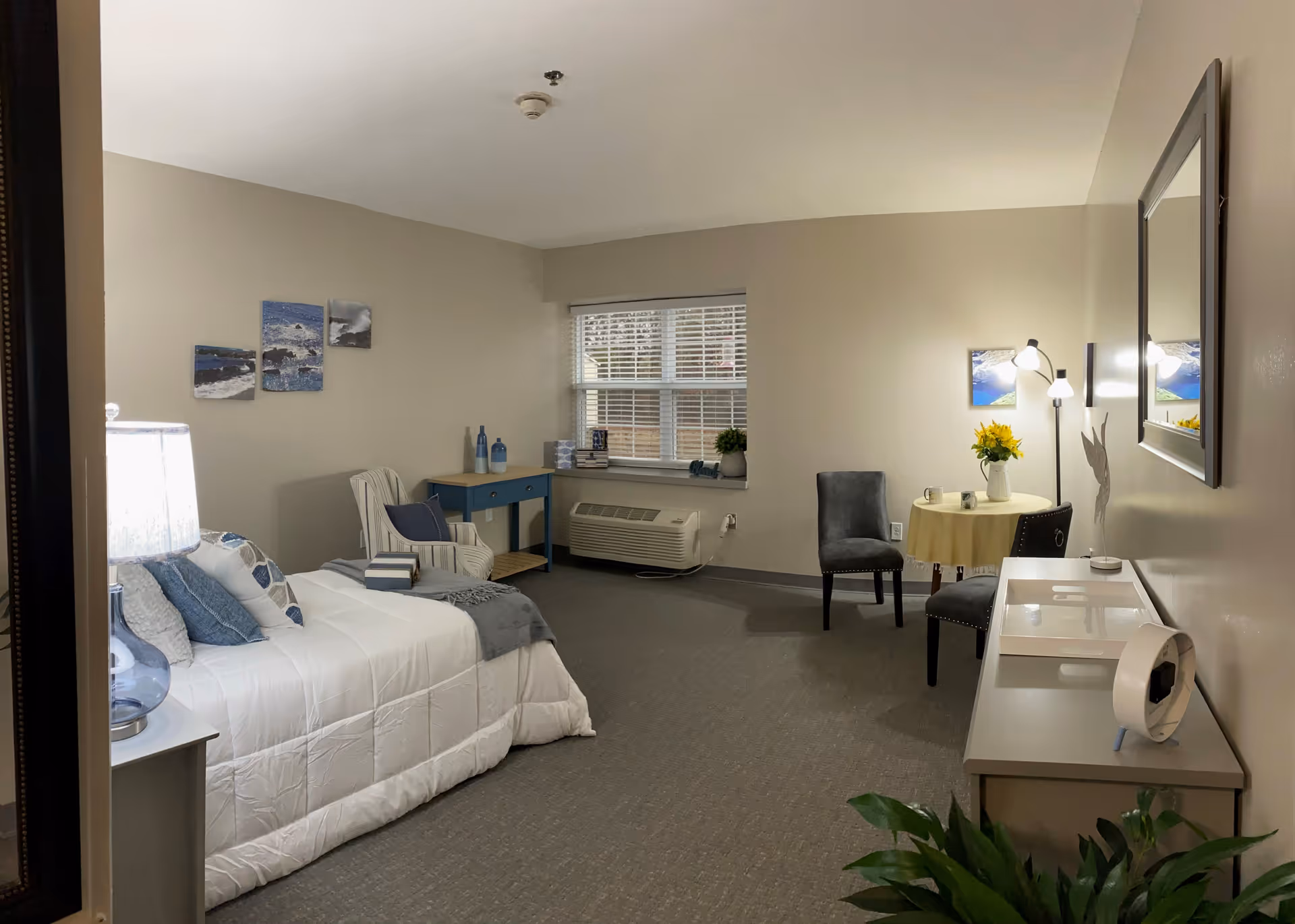 A spacious senior living bedroom with a bed, seating area, and window.