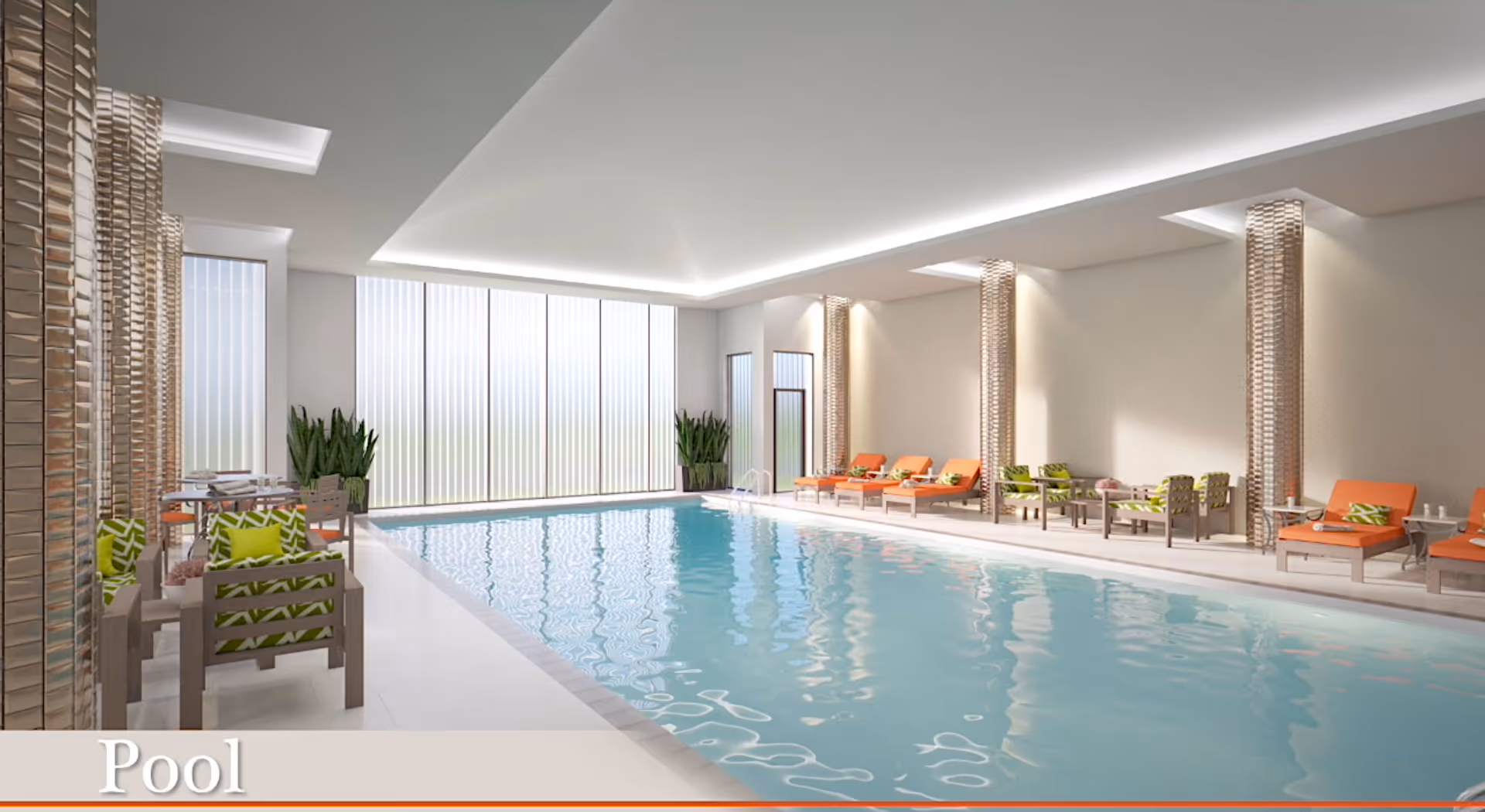 Indoor swimming pool area with clear blue water, surrounded by lounge chairs with orange cushions and green patterned pillows. There are also small tables and chairs along the left side near tall windows with vertical blinds, and decorative columns with lighting.