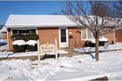 Red brick senior living facility exterior with a snow-covered ground and Welcome Center sign.