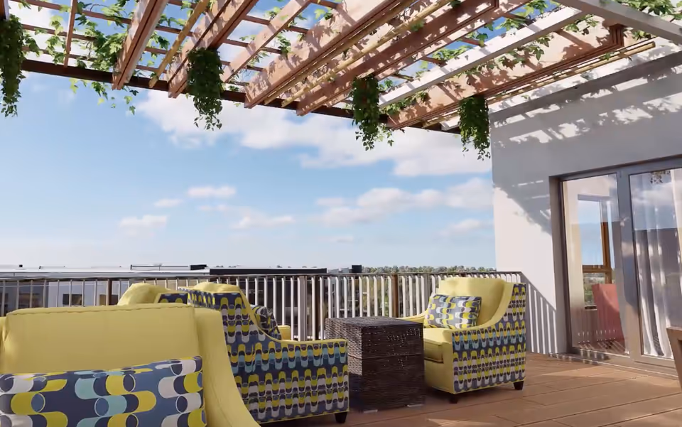 Rooftop patio with yellow patterned armchairs around a wicker table under a wooden pergola with hanging plants and a view beyond the railing.