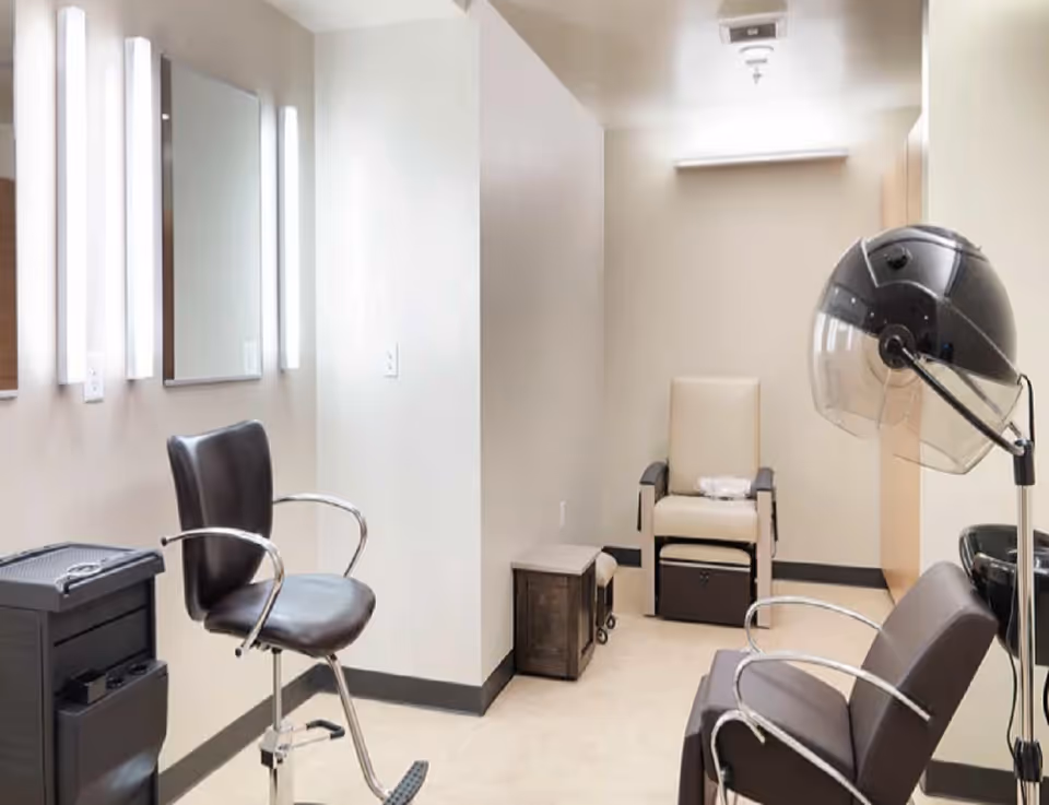 Interior salon room with styling chairs, wall mirrors, and a hooded hair dryer.