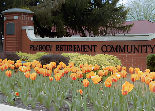 Brick entrance sign reading "Peabody Retirement Community" behind a bed of orange tulips.