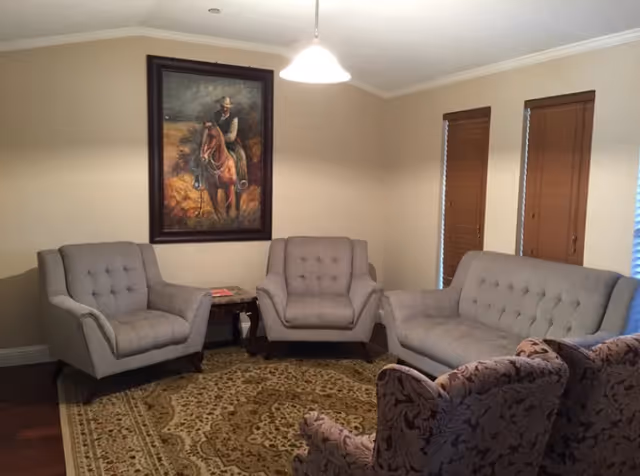 Cozy sitting room with a sofa, three armchairs, patterned rug, and a large framed painting of a horse and rider.