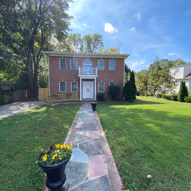 Front view of a brick two-story assisted living building with a manicured lawn and walkway.