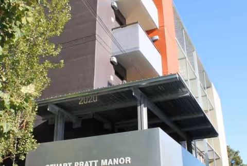 Exterior view of Stuart Pratt Manor building with balconies and a covered entrance