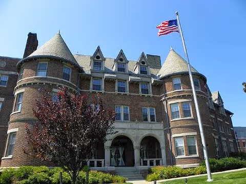Large brick senior living facility with turrets and an American flag at the entrance.
