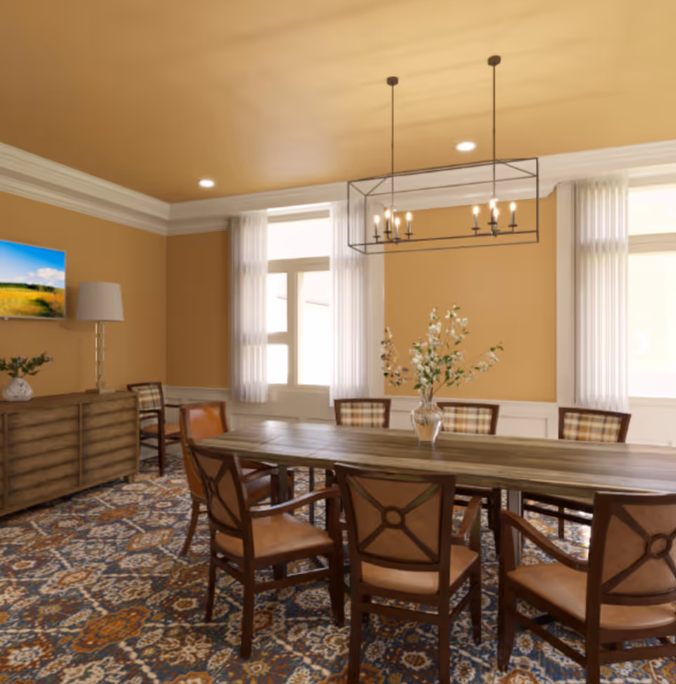 A warmly lit dining room with a long wooden table surrounded by upholstered chairs, a patterned rug, windows with sheer curtains, and a modern rectangular chandelier.