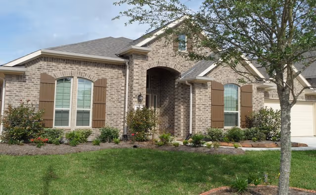 Brick exterior of a senior living facility with arched entry and manicured lawn.