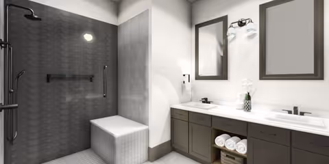 Modern bathroom with a walk-in shower featuring a built-in bench and dark tiled walls. Adjacent to the shower is a double sink vanity with two mirrors, dark cabinetry, and neatly rolled white towels on an open shelf.