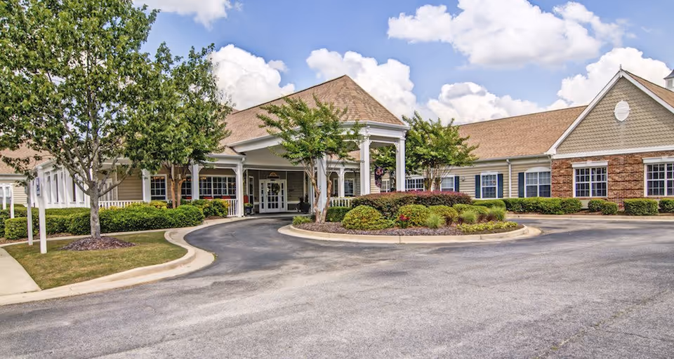 Exterior view of Oaks at Evans senior living facility, featuring circular driveway and manicured landscaping.
