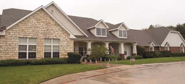 Front view of Brookdale Weatherford senior living building with flags and manicured lawn.