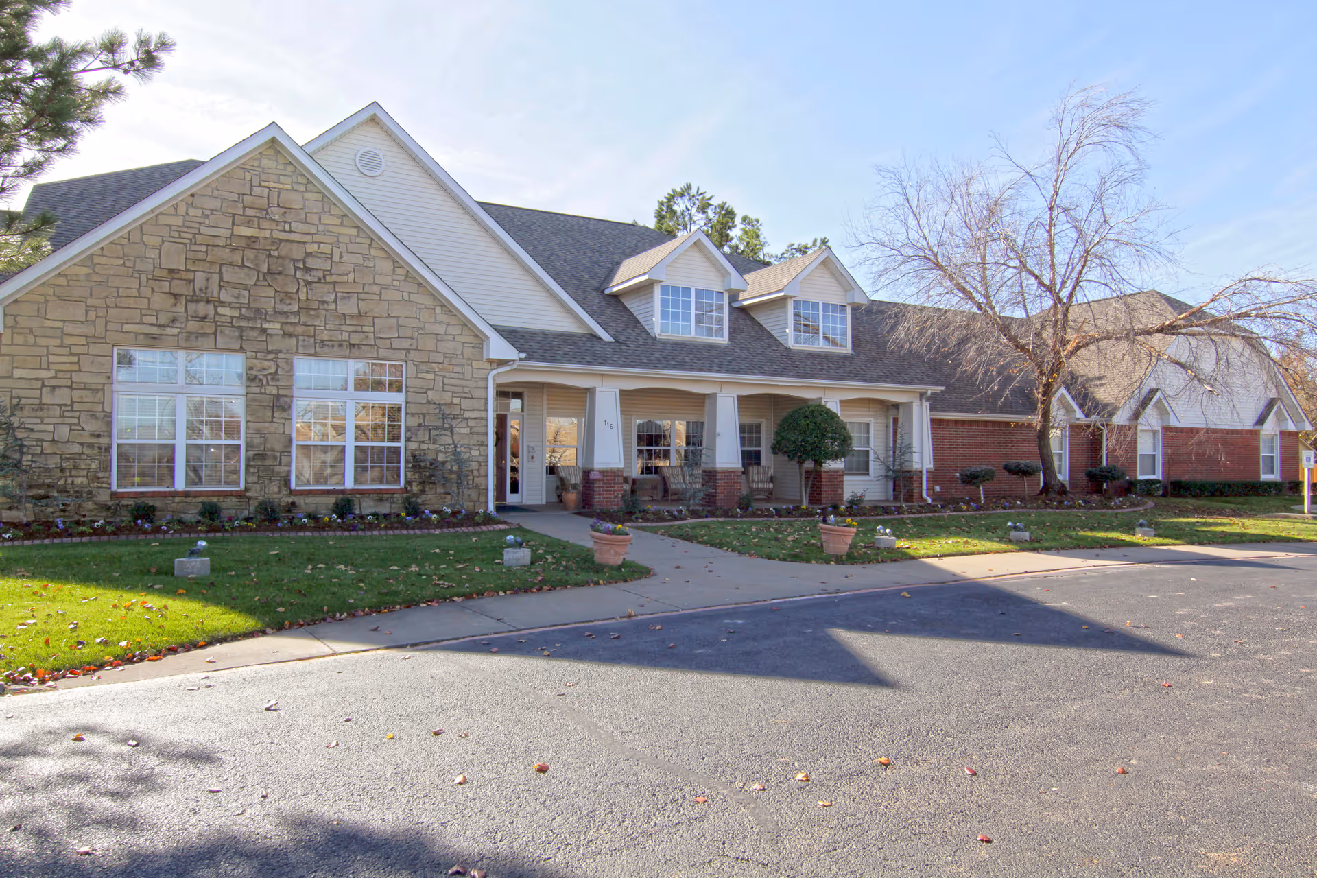 Front exterior of a single-story brick and stone senior living facility with a covered porch and driveway.