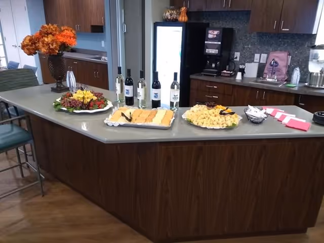 Wood-paneled kitchen island in a common area arranged with platters of hors d'oeuvres, wine bottles and serving utensils.