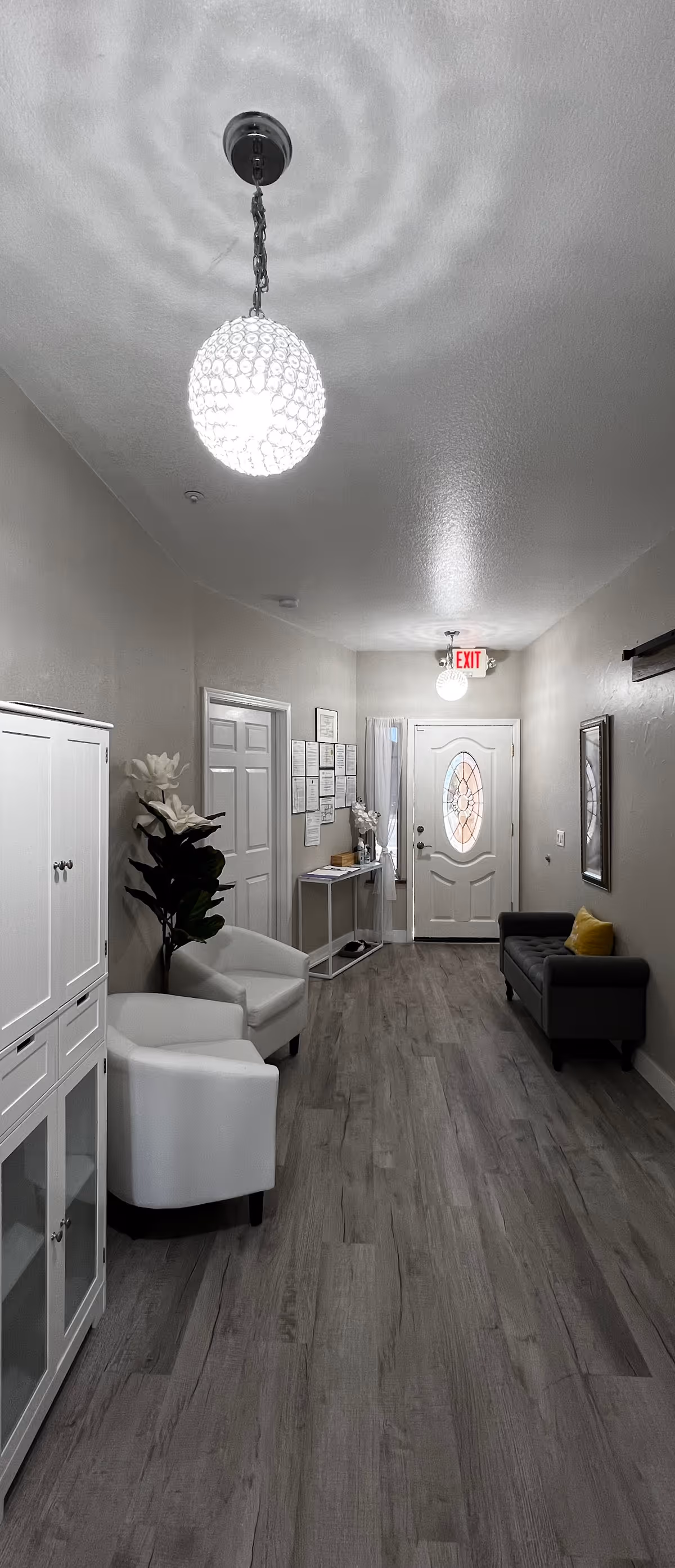 Long interior hallway and entry area with seating, decorative pendant lights, and a front door at the far end.