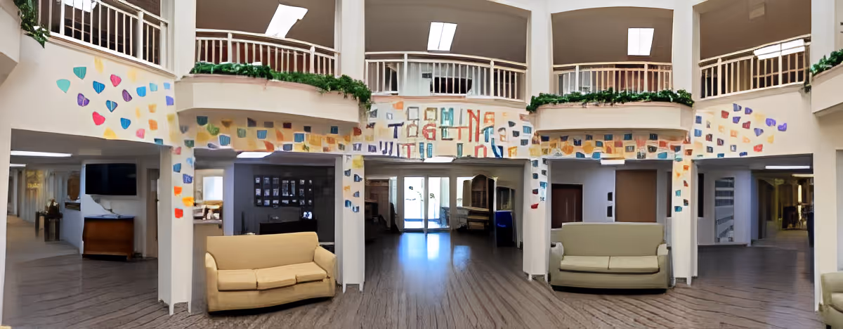 Spacious two-story atrium lounge with sofas, balcony railings, colorful wall art and open hallways.