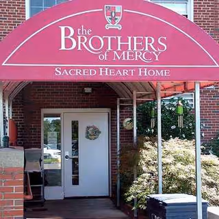 Front entrance of The Brothers of Mercy Sacred Heart Home under a red canopy.