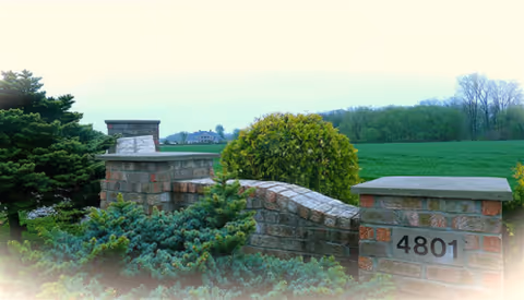 Stone entry wall with greenery and the number 4801 on a brick pillar.
