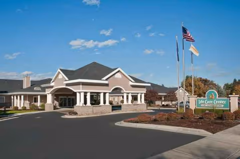 Front view of Life Care Center of Lewiston with entrance, driveway, and flags