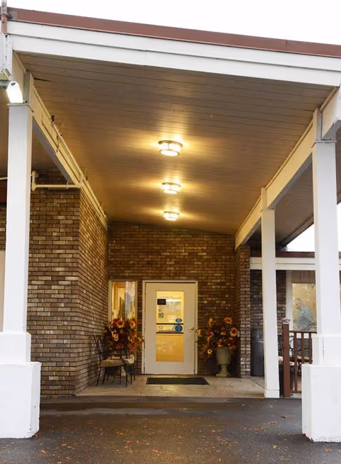 Clearwater Care Center entrance with brick facade, covered porch, doors, and decorative plants.