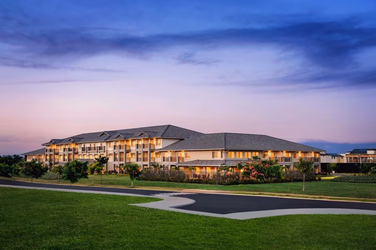 Exterior view of Ilima at Leihano senior living facility with landscaped lawn at dusk