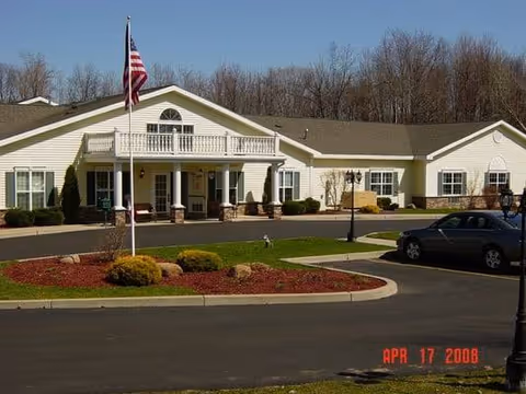 Exterior view of Park Terrace at Radisson, a single-story senior living building with flag and landscaping.