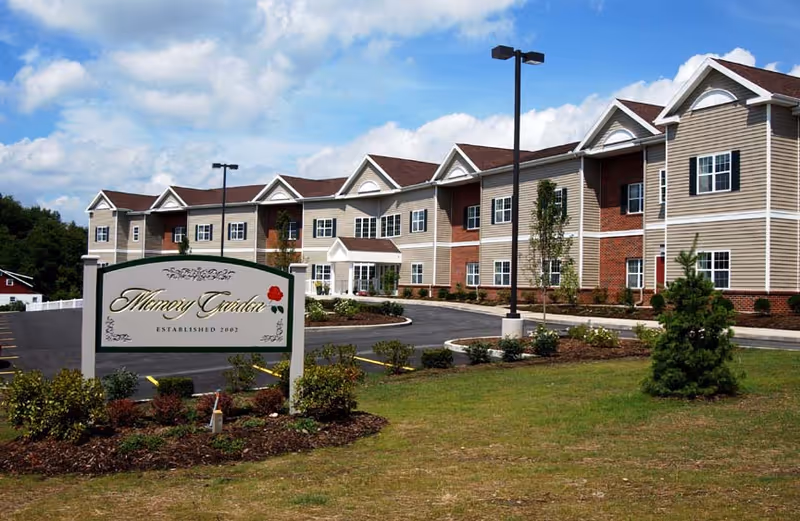 Exterior view of Memory Garden senior living facility with sign and landscaped entrance.