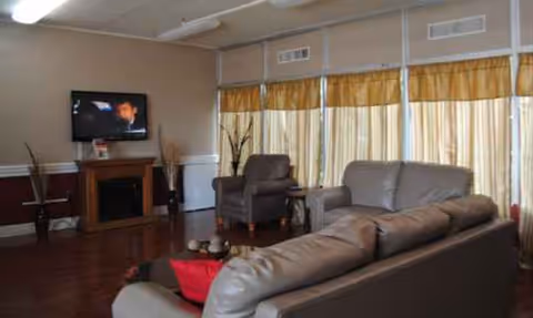 Cozy living room with brown leather couches, a fireplace, TV, and large windows.