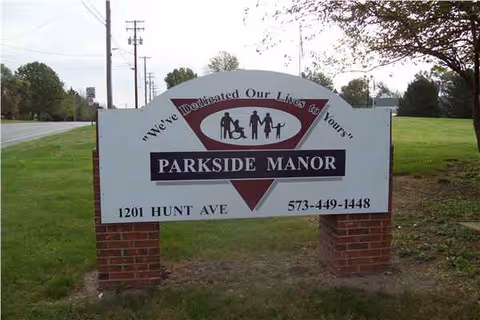Parkside Manor sign on brick posts beside a grassy roadside.