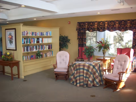 Lounge area with two cushioned chairs, a round table, and bookshelves.