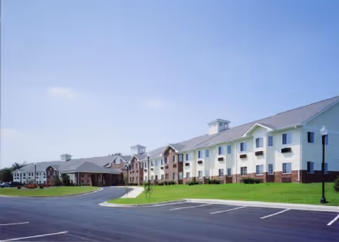 Exterior view of a multi-building senior living facility with green lawn and parking.