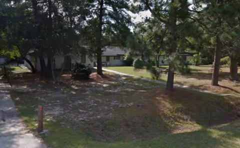 Exterior view of Valley Pines Adult Care Home with trees and a driveway.