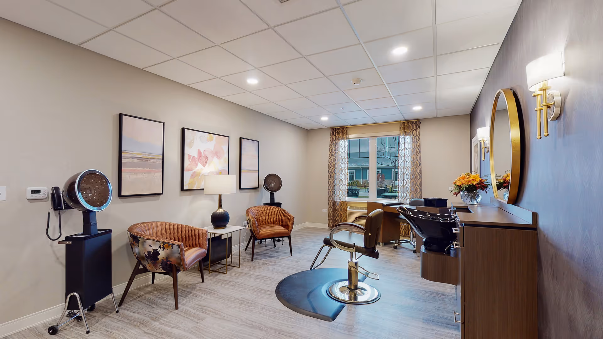 Bright interior salon room with styling chairs, a shampoo station, a small seating area, and a window with curtains.
