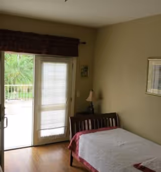 Small bedroom with a single bed next to sliding glass doors opening to a balcony.