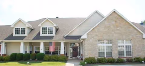 Single-story senior living facility exterior with a covered entrance and manicured lawn.