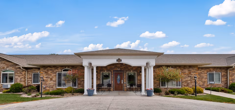 Front view of The Village at Eden Vista senior living facility with stone exterior and landscaped entrance.