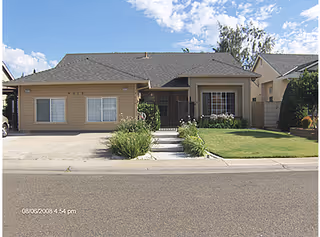 Single-story beige senior living facility with front lawn and walkway.