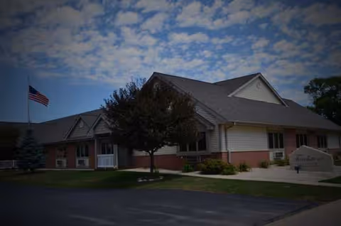 Touchstone Living Center exterior with flag, tree, and a paved entrance.