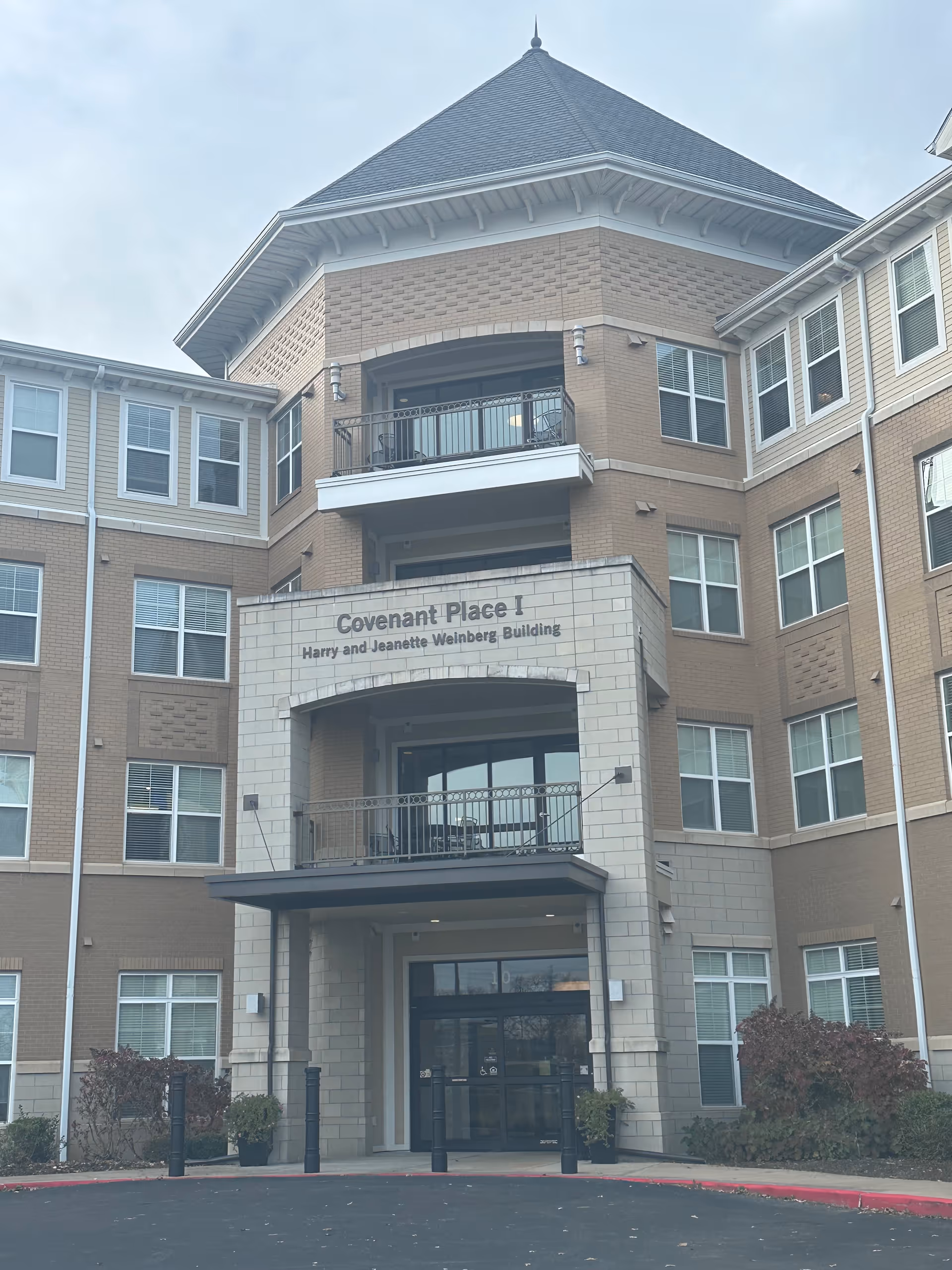 Exterior view of a multi-story senior living facility building named Covenant Place I, Harry and Jeanette Weinberg Building, with a covered entrance, balconies, and multiple windows.