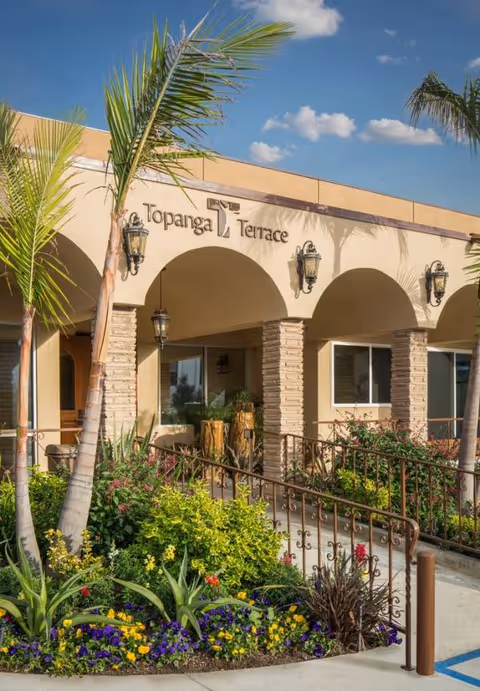 Exterior view of Topanga Terrace entrance with arches and tropical landscaping.