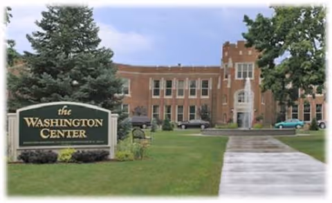 Front exterior of a brick building with a lawn and a sign reading "The Washington Center".