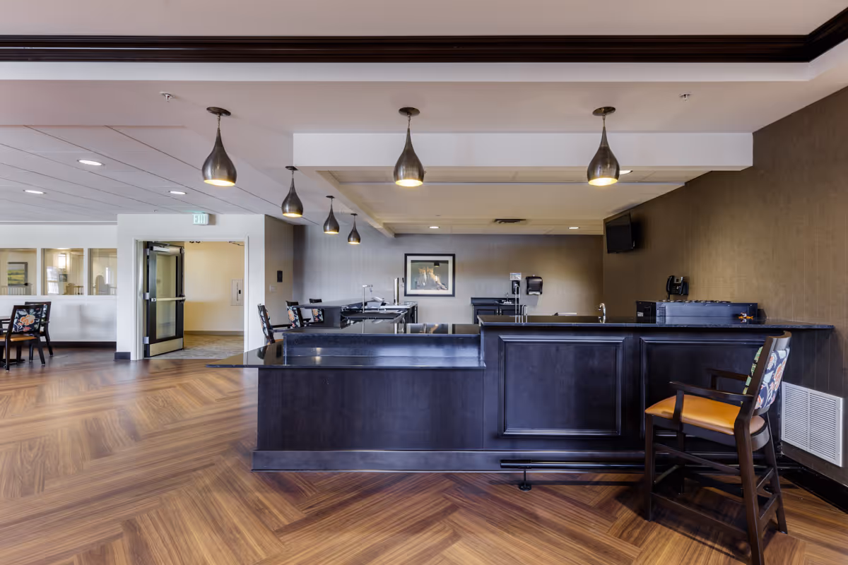 Interior reception area with a dark wood front desk, pendant lights, seating, and herringbone wood flooring.