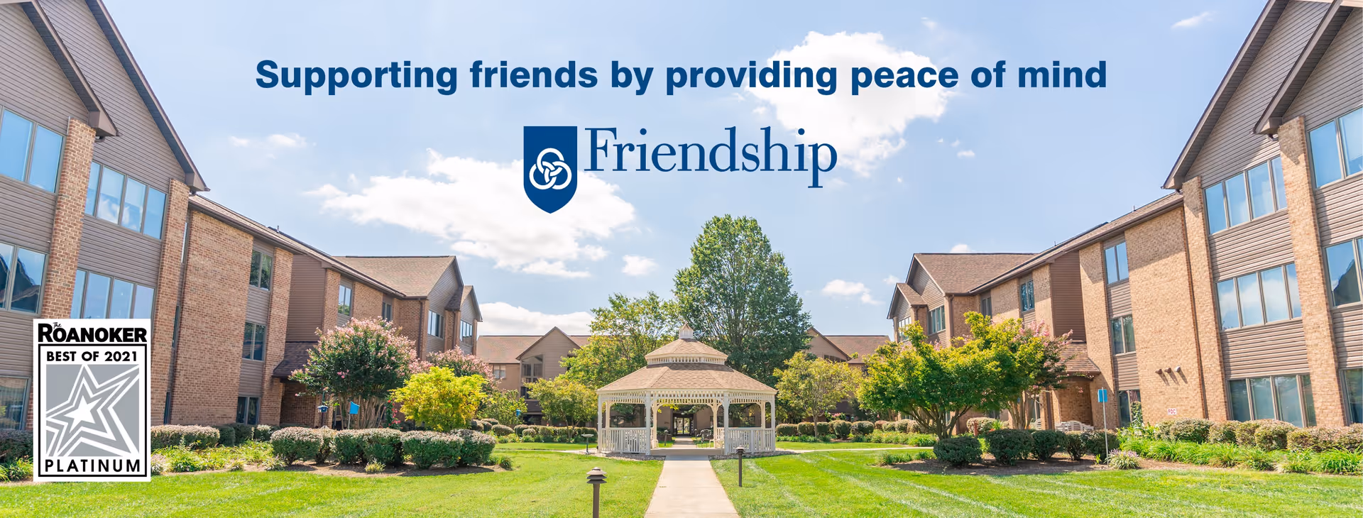 Outdoor courtyard area of Friendship Health & Rehab Center North featuring a central gazebo, surrounded by well-maintained lawns, bushes, trees, and multi-story brick buildings on both sides under a partly cloudy sky.