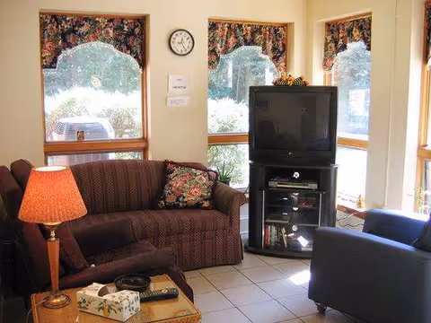 Cozy living room in a senior facility with sofa, lamp, coffee table, and TV.